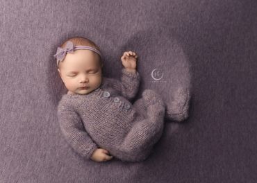 sweet newborn girl in lilac with luxury heart prop during her studio newborn session in Corona.