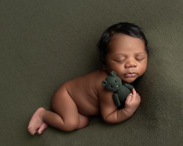 african baby newborn session in moss greens hugging a teddy bear.