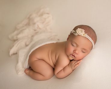 newborn baby girl wrapped in cream wrap during session with best newborn photographer on corona.