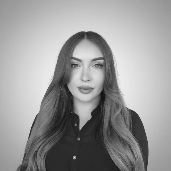 Portrait of a woman with long brown hair wearing a navy blue blouse.