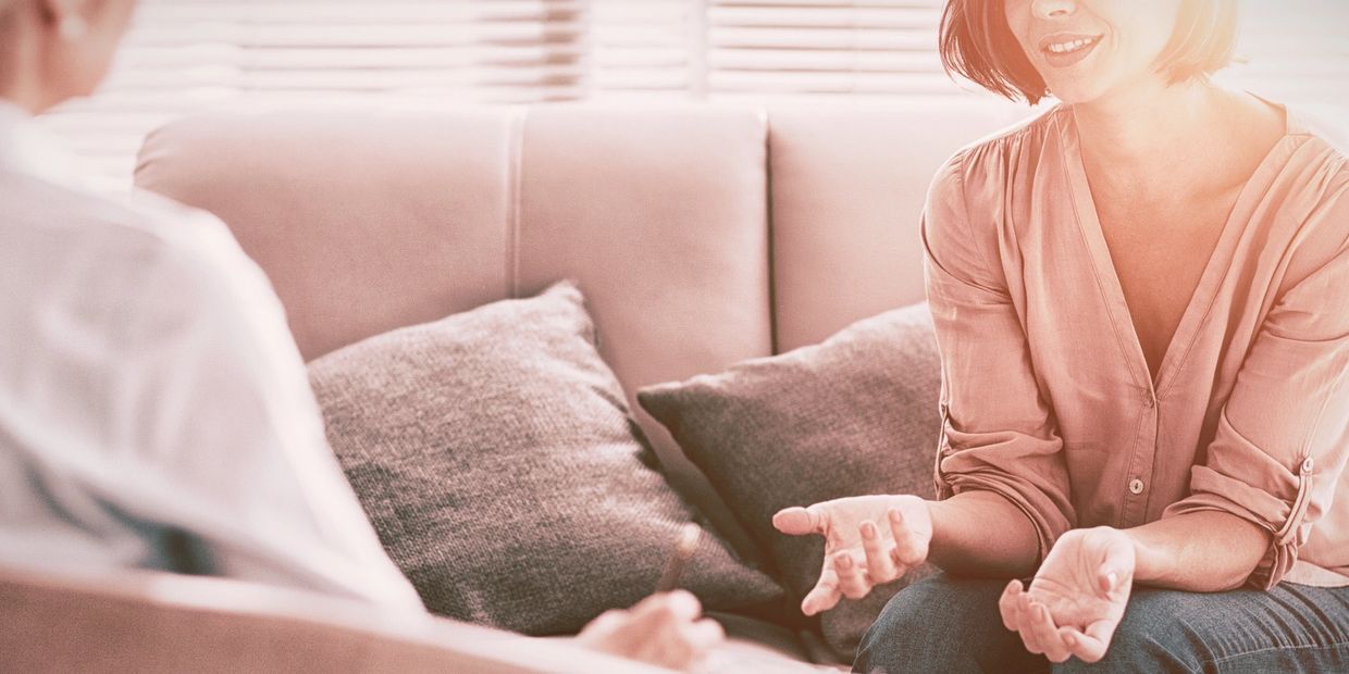 A woman and a man having a conversation on a couch.