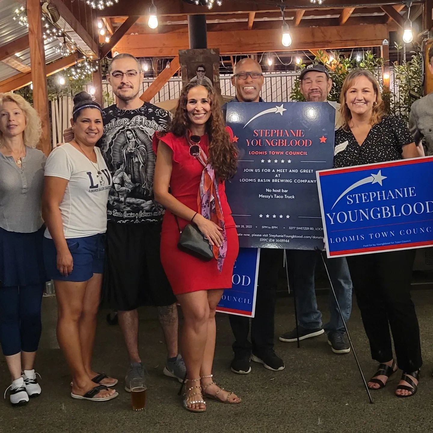 Group of people at a campaign meet and greet event holding Stephanie Youngblood signs.