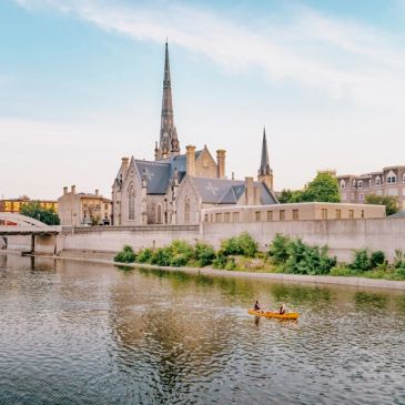 River with a church and boat at sunset.