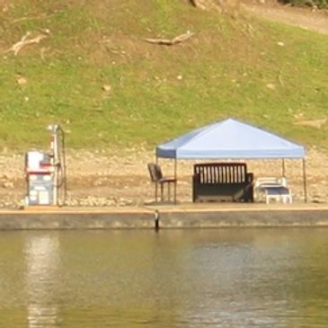 A gas pump and canopy along the river on a dock.