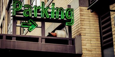Neon green parking sign with an arrow on a building exterior.