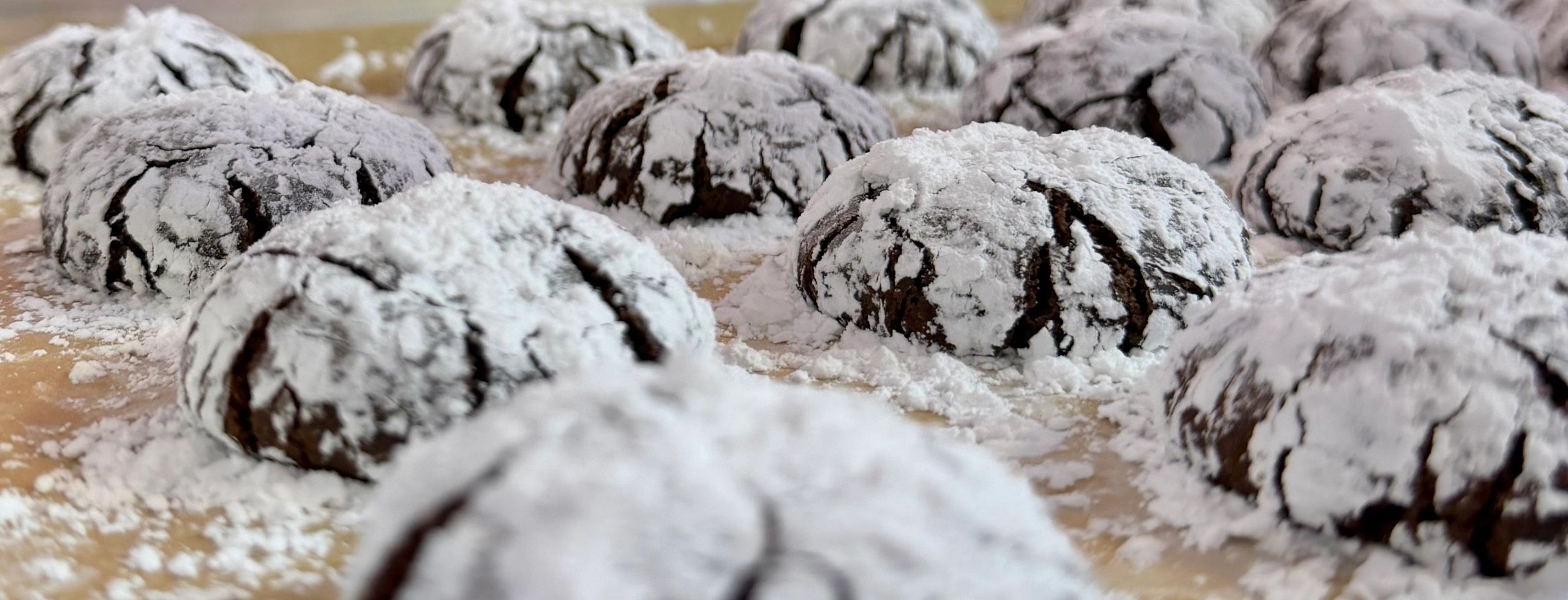 Chocolate crinkle cookies dusted with powdered sugar on a tray.