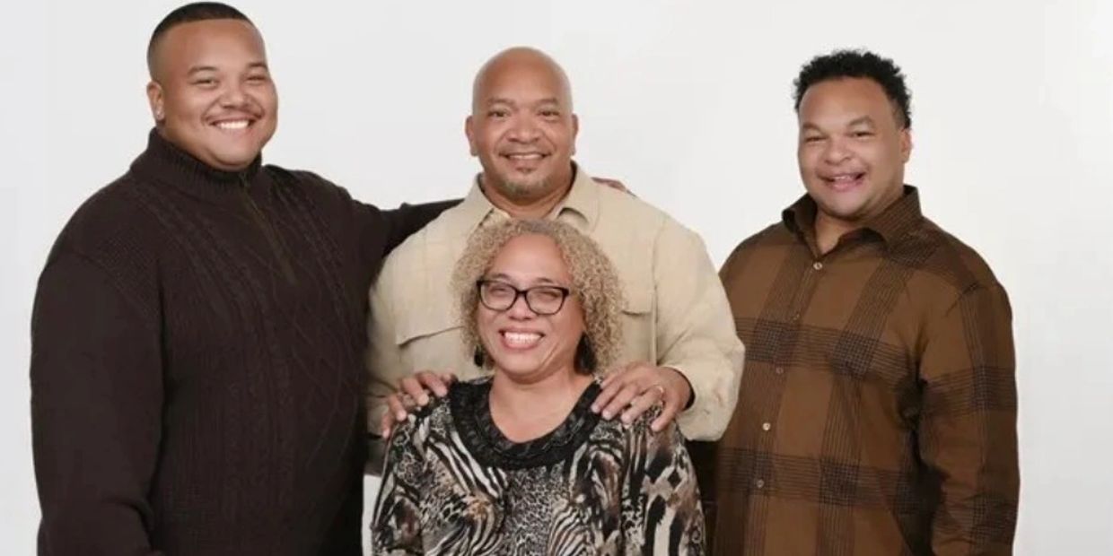A happy family portrait of four people smiling against a white background.