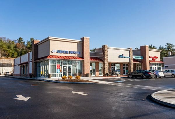 A small shopping center with various businesses on a clear day.