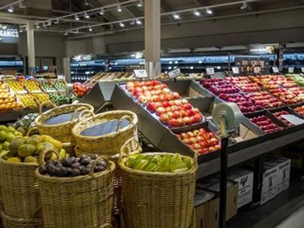 Fresh fruits displayed in baskets and shelves inside a supermarket.