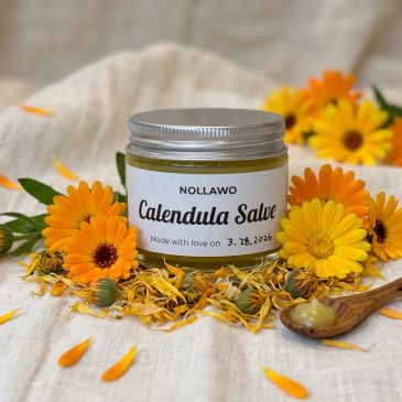 Jar of calendula salve surrounded by calendula flowers.