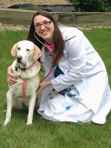 Dr. Lauren smiling with her dog stella who is yellow lab.