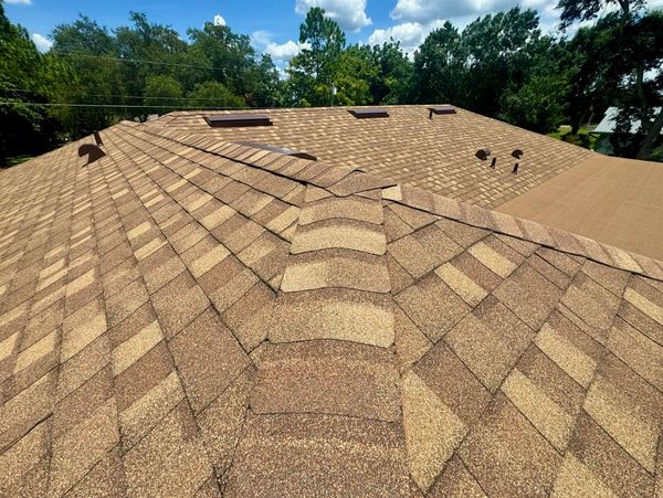 Brown shingled roof under blue sky.