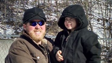 John holding Henry in front of a waterfall.