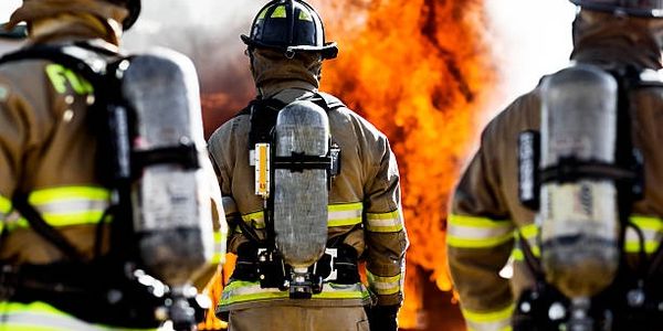 Firefighters in protective gear facing a large blaze during firefighting efforts.