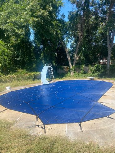 blue pool cover over pool with slide and step bump out