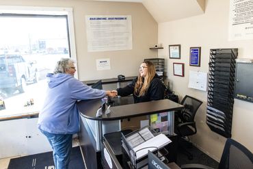 Expert Auto Service front desk staff assisting a customer with DMV paperwork and vehicle registratio