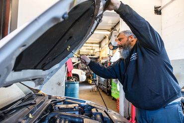 Expert Auto Service technician inspecting components under the hood during a brake and safety check