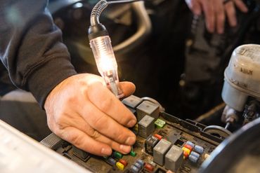 Expert Auto Service technician diagnosing electrical and brake system components using professional
