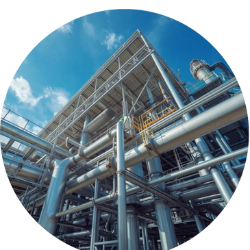 Large industrial pipes and metal structures at a factory under a blue sky.