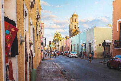 Colorful street with colonial buildings and a church tower in the background.