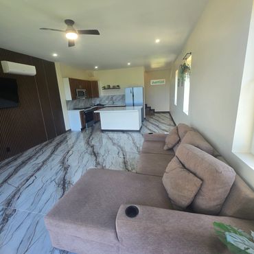 Modern open-plan living room with marble floors and a large brown sectional sofa.
