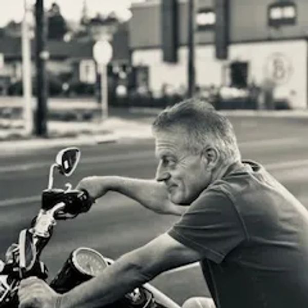 A man confidently riding a motorcycle on a street.