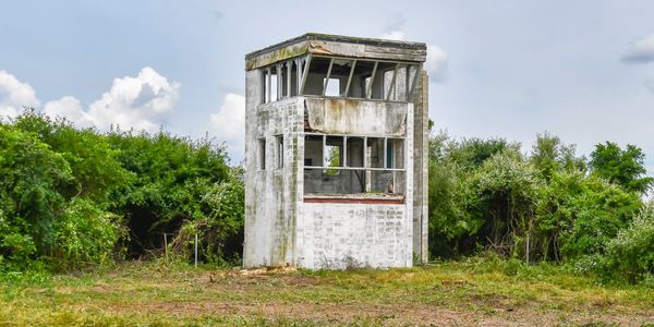 Abandoned old watchtower in grassy field.