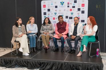 Leanne Zaccar speaking on stage with a panel of speakers for international Yoga day