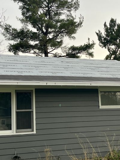 House with a newly installed underlayment roof and gray siding.