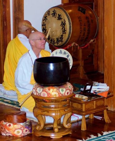 Two monks drumming and chanting during a ceremony.