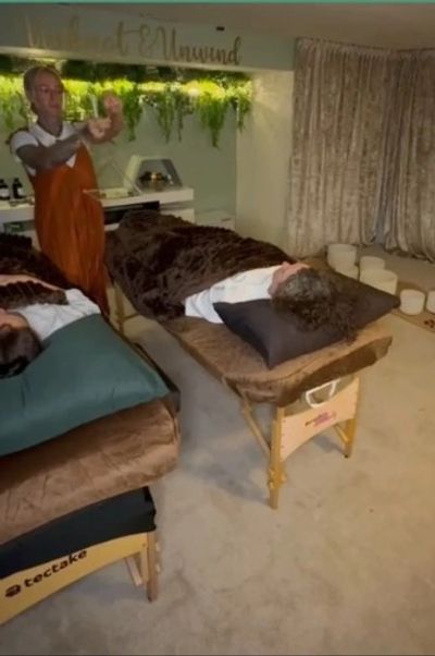 Lady holding Crystal singing pyramid, two clients on bed receieving sound therapy.