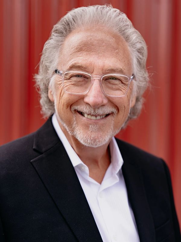 Smiling elderly man with glasses and white hair.