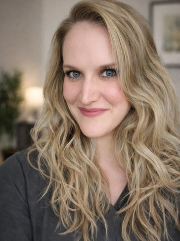 Smiling woman with long, wavy blonde hair and blue eyes.