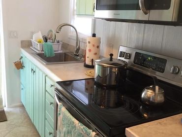 Kitchen area with sink. full stove, oven and microwave.
