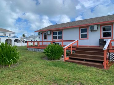 Outside of three-plex with stairs that go from the yard up to the deck.