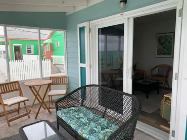 Outdoor seating area with multiple chairs to sit, and a sliding door to the inside.