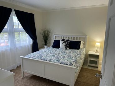 Queen bedroom with lamp, area rug, and neatly made bed.