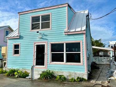 Front of a house that is painted blue with pink trim.
