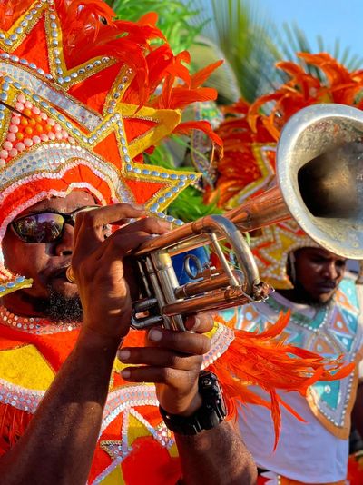 Brightly dressed man playing a trumpet in a Junkanoo parade.