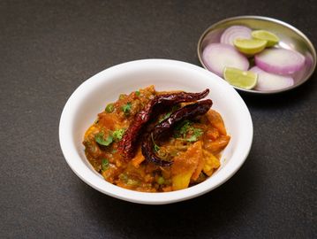 Spicy Indian curry garnished with dried red chilies and fresh herbs.