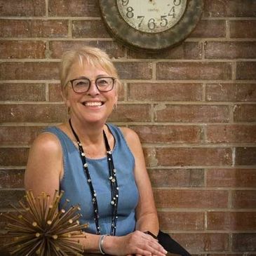 A business women smiling in front of a brick wall.