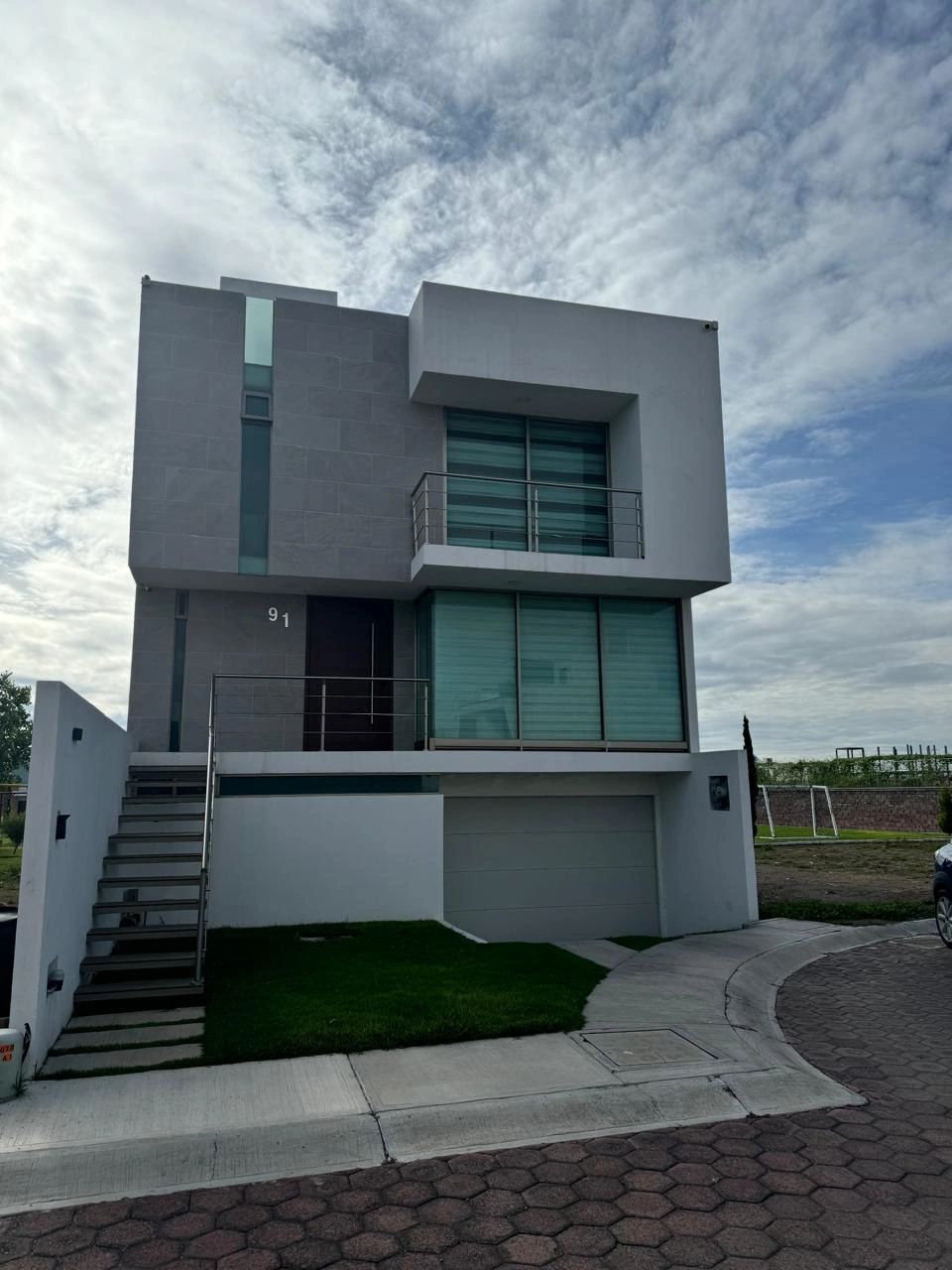Casa moderna de dos pisos con fachada gris y blanca.