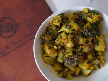 A bowl of herbs and chopped potatoes