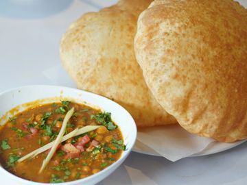 A Chana Bhatura with a bowl of sauce