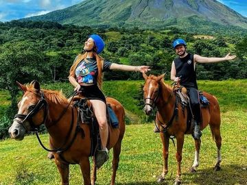 Couple on horseback with a scenic volcano in the background.