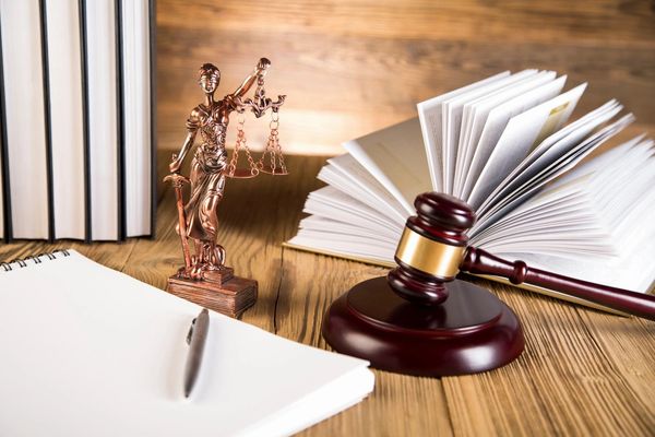 Lady of justice, wooden & gold gavel and books on wooden table and wooden background