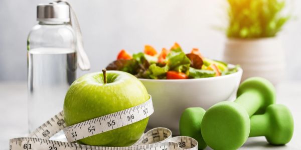 Healthy lifestyle items including green apple, dumbbells, salad, and water bottle.