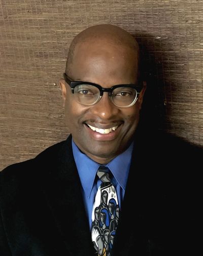 black professional man in a suit with glasses and a big smile, Michael Francis, MBA