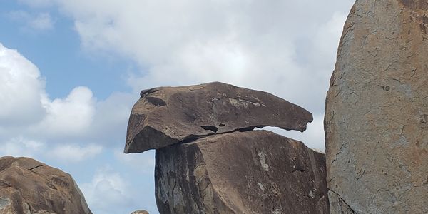 A rock formation resembling a bird's head against a blue sky.