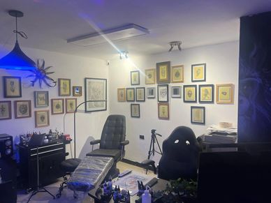Tattoo studio room with framed art on walls and tattoo equipment.